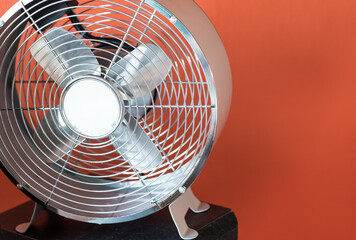 Cooling fan in retro style in front of an orange wall