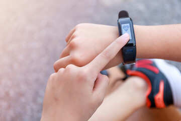 Close up Girl using smartwatch touching button and touchscreen on active sports. Finger touch button on smarth watch. Girl set smart watch before running on road.