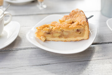 Piece of dutch apple pie on a white table on light grey table