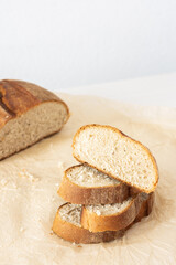 Loaf of homemade bread with sliced bread from wheat and seeds on parchment paper