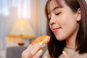 Young woman relaxing and eating donut by ordering delivery,  at home on holiday.  junk food, unhealthy meal, obesity risk.