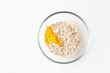 Bright yellow turmeric powder in a bowl of oatmeal on a white background