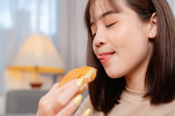 Young woman relaxing and eating donut by ordering delivery,  at home on holiday.  junk food, unhealthy meal, obesity risk.
