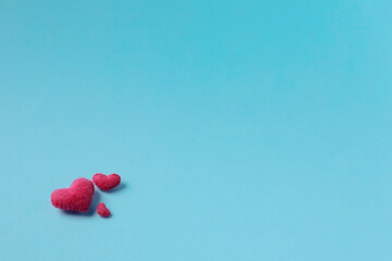 Three felt handmade pink hearts are on a blue background. The concept of the family, Valentines day. A symbol of love happiness and devotion. Copy space.
