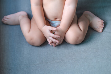 Little baby sitting W posture on the gray sofa,Which is called W-sitting knees bent and feet...
