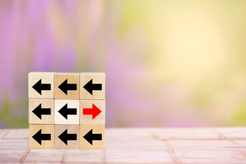 Wood block red arrow pointing the opposite way disruptive from the black arrows on table wooden....