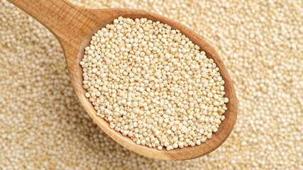 quinoa seeds in wooden spoon and on background. top view