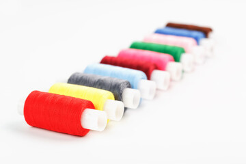 Sewing threads of different colors on reels on a white background. Free space, close-up. Isolate