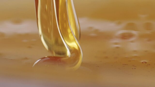 Macro close up shot of dripping honey. Seamless gold background. Soft commercial light from left and right.