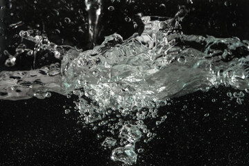Obraz na płótnie Canvas Water splashing as it's poured into aquarium tank, black background