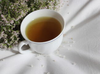 Baldriantee und Baldrianblüten auf einem Kopfkissen