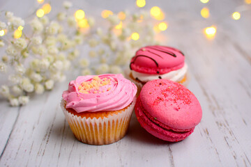 Close-up of bright pink pastries and macaroons on a light wooden background