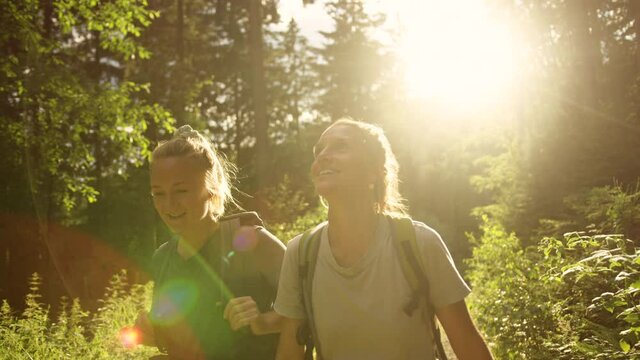 Two women hiking in the mountains with backpacks. Girls on a hike breathing fresh air oxygen. Back to nature