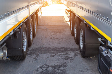 Two new truck semi-trailers are parked in a truck stop. Cargo transportation concept axle load,...