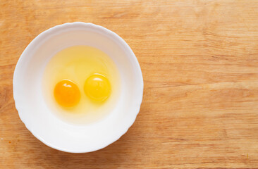 Two chicken eggs, homemade and factory, are broken in a glass plate. Difference concept of homemade natural eggs from store-bought, organic, copy space