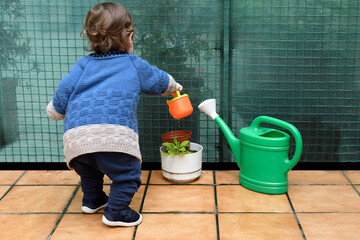 He babies about eighteen months old playing the gardener watering the plants