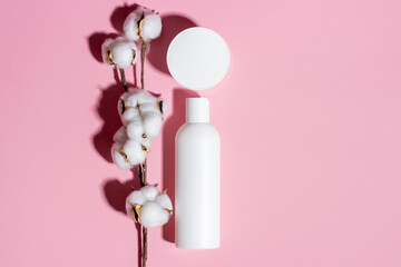 Natural cosmetics in a white bottle top view on a pink background.