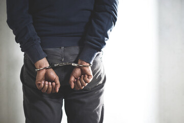 Prisoner male criminal standing in handcuffs with hands behind back. thief.