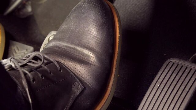 A man's foot pressing accelerator, suddenly, hits the brake, wearing black leather shoes, HONDA car, Tokyo, Japan. March 2020. Camera fixed, extreme close-up, high angle view.
