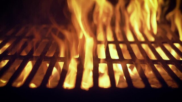 Intense fire from burning coal over a barbecue grill, slow motion, camera moving.