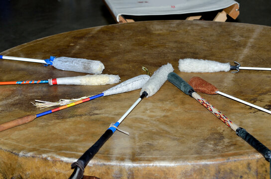 Several handmade drumsticks resting on a powwow drum.