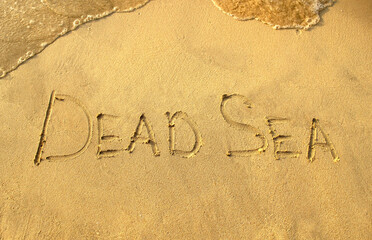 Dead Sea words on beach sand. Dead Sea phrase is written on a sand. 