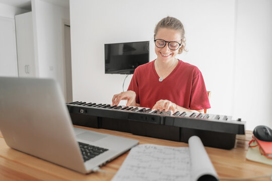 Young girl woman learns to play the piano with a teacher on a video conference, Education video calls self education.
