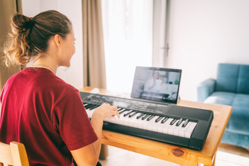 Young girl woman learns to play the piano with a teacher on a video conference, Education video calls self education.
