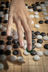 close up of player hand with weiqi stone to make a move in Go game