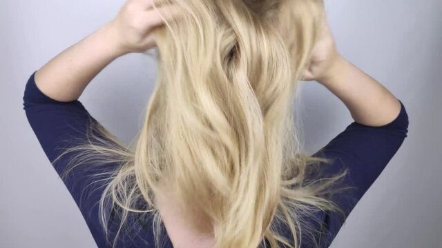 Natural blonde tosses and fluffs her hair in front of the camera. The concept of proper hair care. Slow motion
