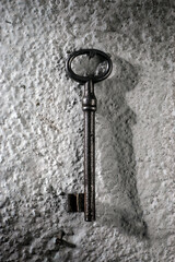 Close up of metal vintage key on grunge wall indoors. Nobody