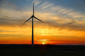 Obraz premium Sunny sunset with beautiful clouds and windmill silhouette