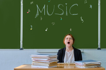 The school music teacher yawns during the lesson. Boring learning to play musical instruments