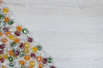 Multicolored candies in a transparent package on a background of bleached wood.