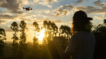 Boy flying a drone at sunset in brazil