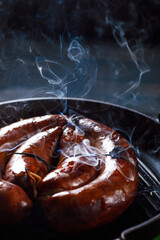 Homemade sausage cooked on a grill, with tomatoes.