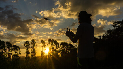 Fototapeta premium Boy flying a drone at sunset in brazil