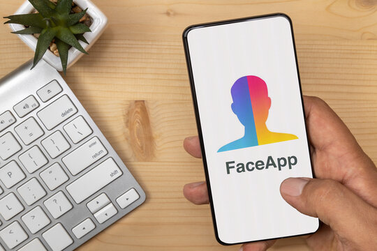 Lutsk, Ukraine - July 17, 2020: Hand Holding and tapping smartphone with FaceApp Logo on it with according text.