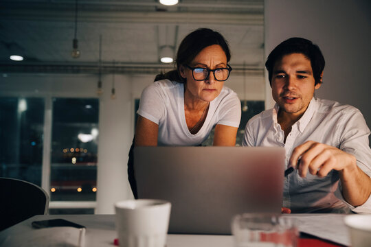 Confident businesswoman planning strategy with businessman during late night meeting at office