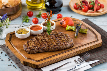 Fresh delicious juicy steak with vegetables on wooden background.