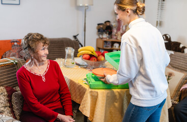 Volunteer serving a meal to senior woman in assisted living program