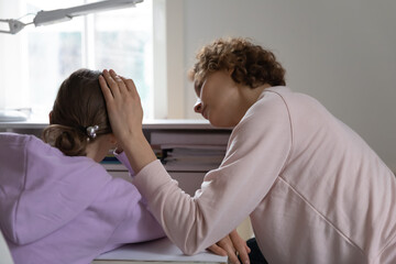 Rear view caring mother comforting upset depressed teenage daughter, touching head, expressing...