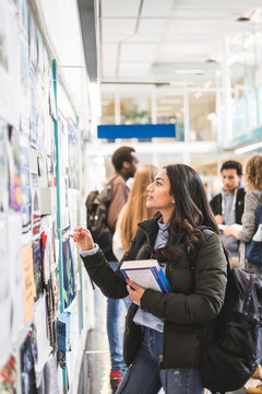 Young female student reading posters in university