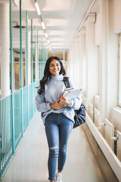 Portrait of young female student walking in corridor of university