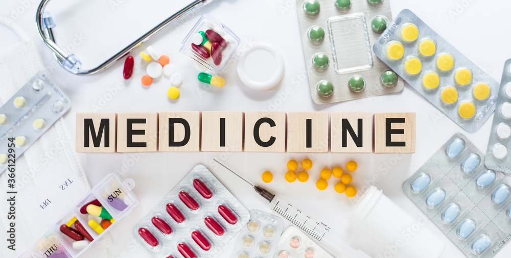 Wall mural MEDICINE medicine word on wooden blocks on a desk. Medical concept with pills, vitamins, stethoscope and syringe on the background. Healthcare imsge for hospital, clinic and medical business