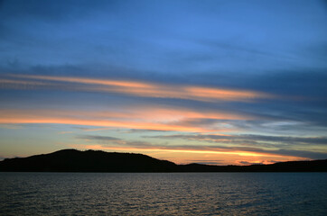 Orange streaks of light from the sun against the dark blue evening sky