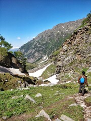 Fototapeta premium Manali, India - June 15th 2019: A Solo hiker climbing down a narrow snowy/Glacial valley in Indian Himalayan Mountain.