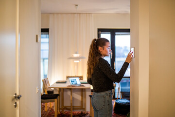 Teenage girl using digital tablet mounted on wall at home