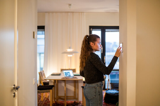 Teenage girl using digital tablet mounted on wall at home