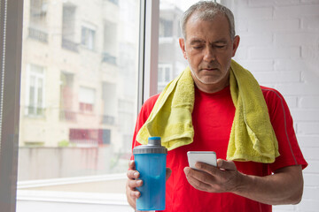 man doing sports with towel and bottle of water using mobile phone